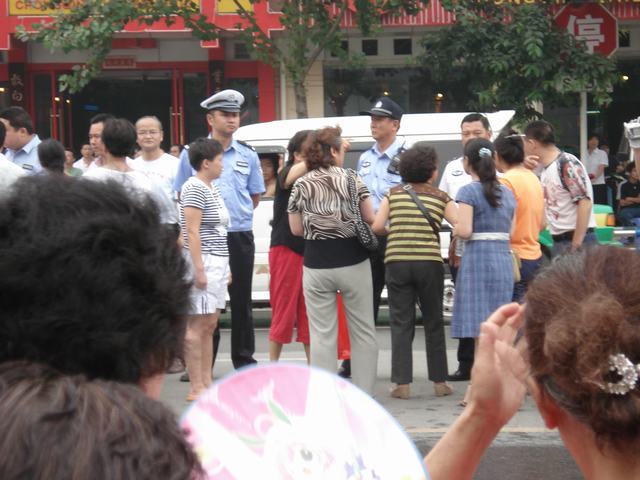 人群向警察领导说明有一老太太心脏病发希望通知急救车来